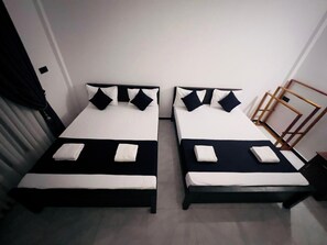 Duas camas de solteiro com roupa de cama preta e branca, uma cabeceira de madeira e uma pequena mesa de cabeceira.