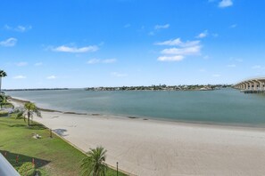 Una spiaggia con vista libera sull'oceano, una battigia sabbiosa e un skyline urbano in lontananza.