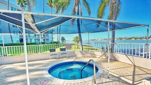 A pool area with a covered seating area, a sign indicating a 15-minute time limit, and a view of the sea. - Bahia Del Mar 7-404 - Point Paradise (St. Petersburg)