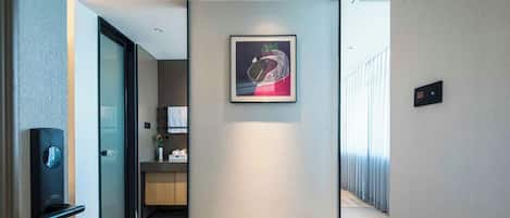 A modern hallway with a framed artwork on the wall, a door with a handle, and a light switch.