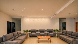 A modern interior with grey sofas, a wooden coffee table, and a wall with motivational text. - S By Z Hotels HSR (Bengaluru)
