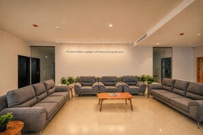 A modern interior with grey sofas, a wooden coffee table, and a wall with motivational text. - S By Z Hotels HSR (Bengaluru)