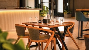 A modern dining area with a wooden table, chairs, and a bar counter. - S By Z Hotels HSR (Bengaluru)