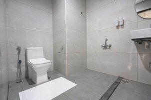 A modern bathroom with a toilet, shower, and sink.