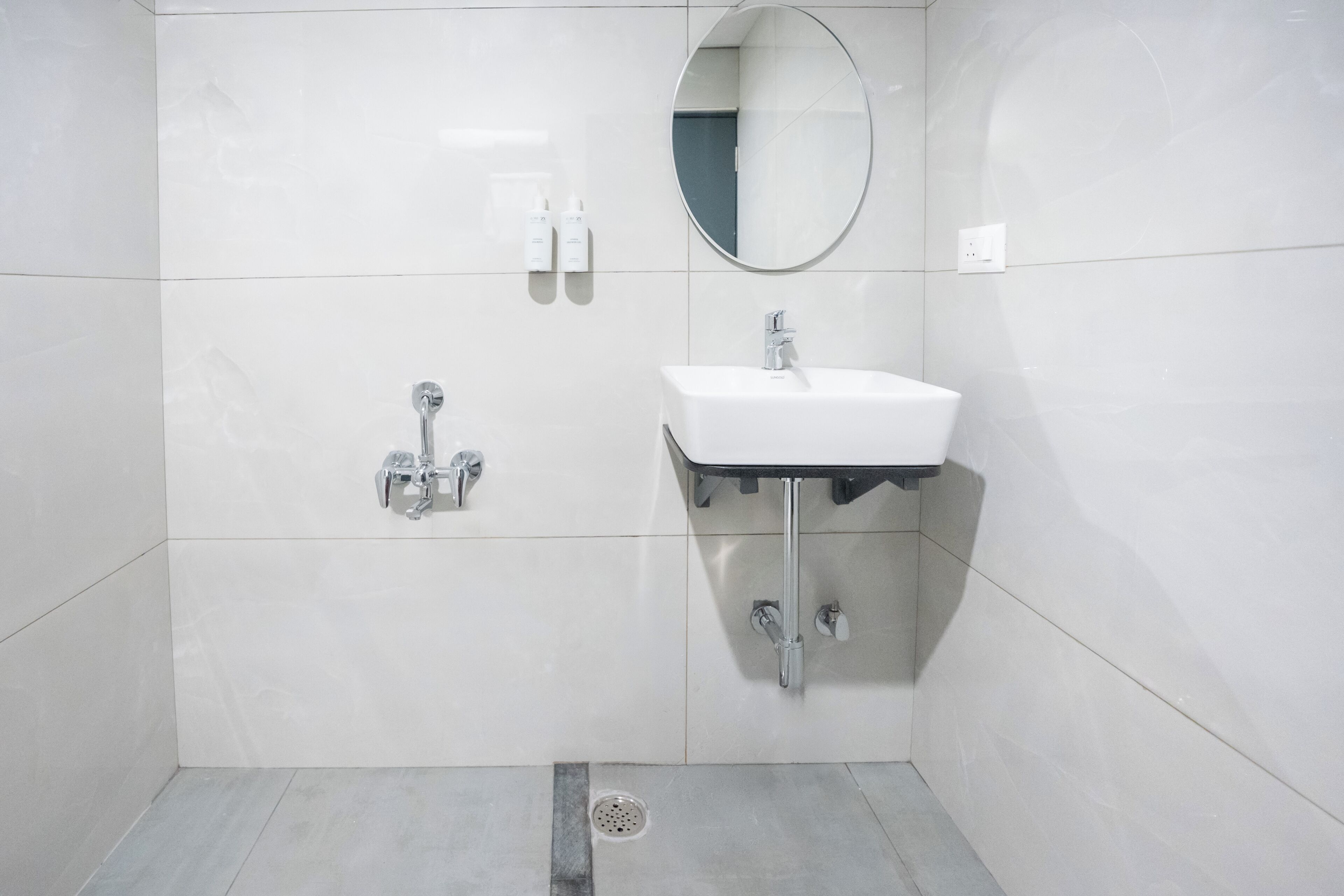 Ein Badezimmer mit einem weißen Waschbecken, einem Spiegel und zwei Wasserhähnen.