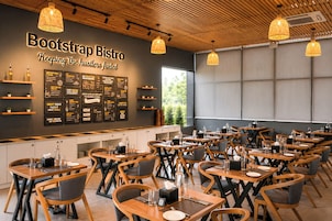 A restaurant interior with multiple tables and chairs, a wall with menu boards, and hanging pendant lights.