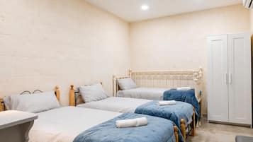 A room with three single beds, a wardrobe, and a small table.