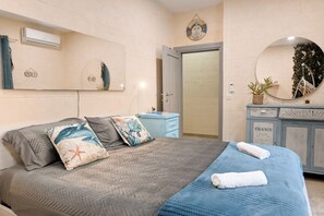 A bedroom with a bed, a nightstand, a dresser, a mirror, and a door. - Xlendi bay Wonderfull 3 bdr Apart Gozo (Munxar)