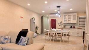 A modern living room with a sofa, dining table, and kitchen area. - Xlendi bay Wonderfull 3 bdr Apart Gozo (Munxar)