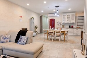 Una sala de estar moderna con un sofá, una mesa de comedor con sillas y una zona de cocina con armarios y electrodomésticos.
