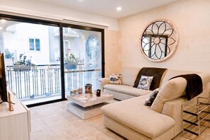 A modern living room with a sofa, coffee table, and a decorative wall piece. - Xlendi bay Wonderfull 3 bdr Apart Gozo (Munxar)