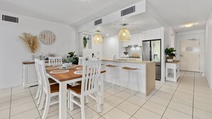 Eine moderne Küche mit weißen Schränken, einem Holztisch und Pendelleuchten.