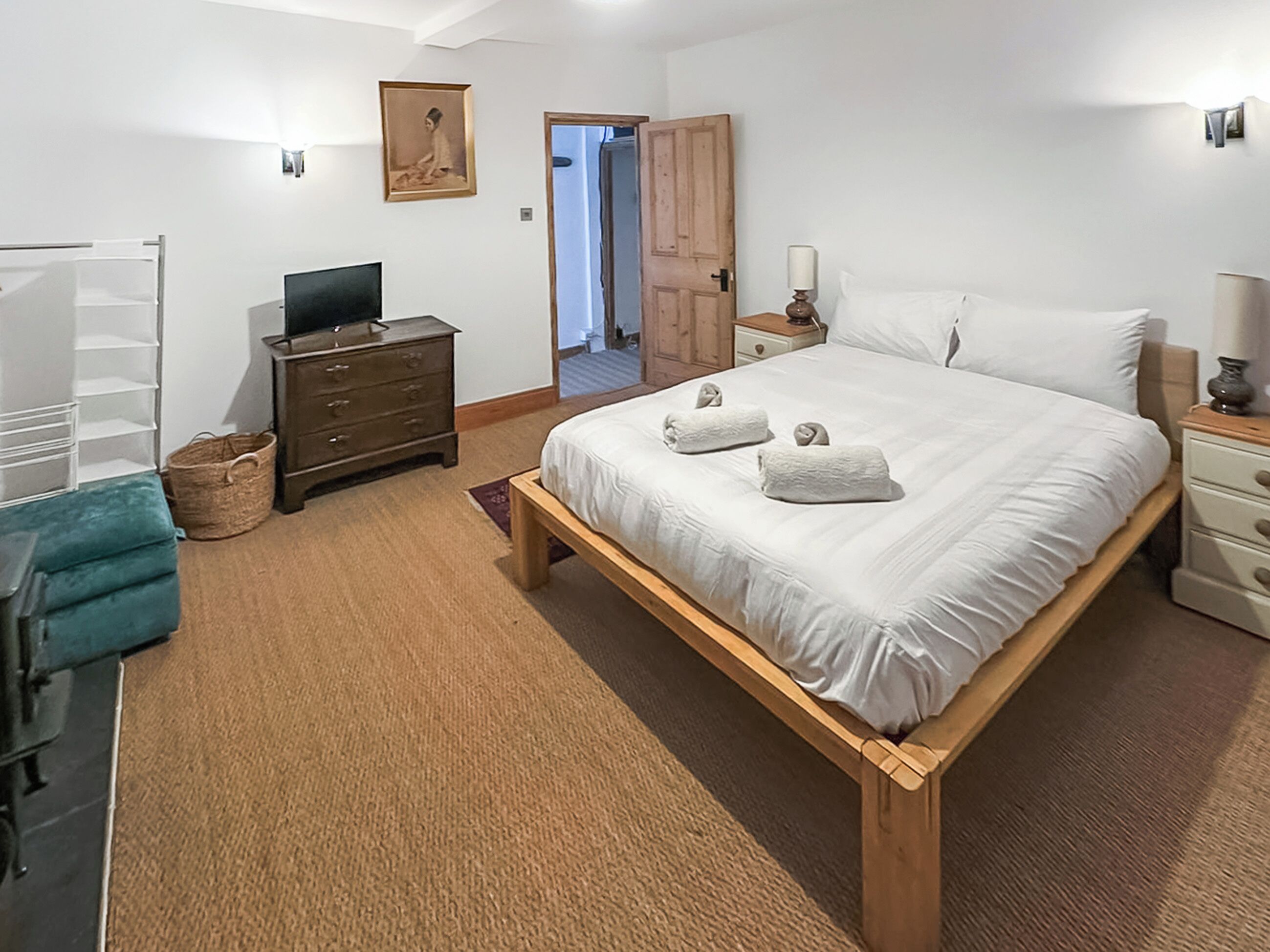 Ein Schlafzimmer mit einem hölzernen Bett, einem Fernseher, einem Kleiderschrank und einer Tür zu einem anderen Raum.