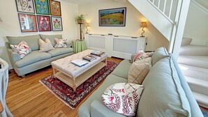 Ein Wohnzimmer mit Sofa, Couchtisch, einem gemusterten Teppich und einer Treppe.
