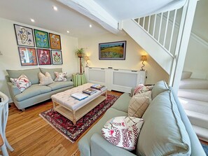Ein Wohnzimmer mit Sofa, Couchtisch, einem gemusterten Teppich und einer Treppe.