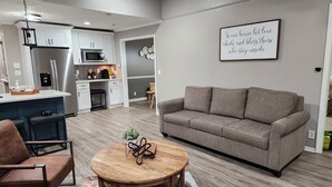 A modern living room with a grey sofa, a wooden coffee table, and a brown leather chair. - Stylish Lilburn/Stone Mountain Retreat w/Theater Room, Bar and 2nd Kitchen (Lilburn)