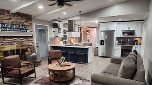 A modern living room with a stone accent wall, a fireplace, leather chairs, a round wooden table, and a brown leather sofa. - Stylish Lilburn/Stone Mountain Retreat w/Theater Room, Bar and 2nd Kitchen (Lilburn)