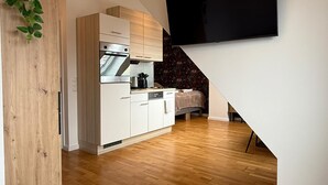 Una cocina moderna con armarios blancos, horno empotrado y televisor montado en la pared.