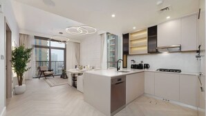 A modern kitchen with a central island, built-in appliances, and a dining area with a view. - Calm & Stylish 1Bedroom in Hadley Heights JVC (Jumeirah Village Circle (JVC))