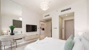 A modern bedroom with a large bed, a TV, a desk, and a mirror. - Calm & Stylish 1Bedroom in Hadley Heights JVC (Jumeirah Village Circle (JVC))