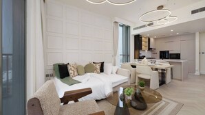 A modern living room with a sofa, a glass coffee table, and a kitchen area in the background. - Calm & Stylish 1Bedroom in Hadley Heights JVC (Jumeirah Village Circle (JVC))
