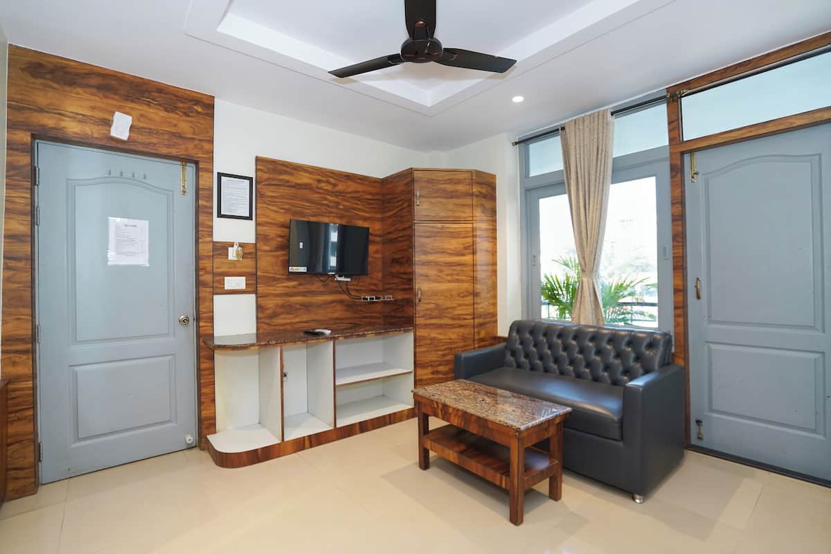 A modern living room with a sofa, a coffee table, a TV mounted on a wooden wall, and a ceiling fan.