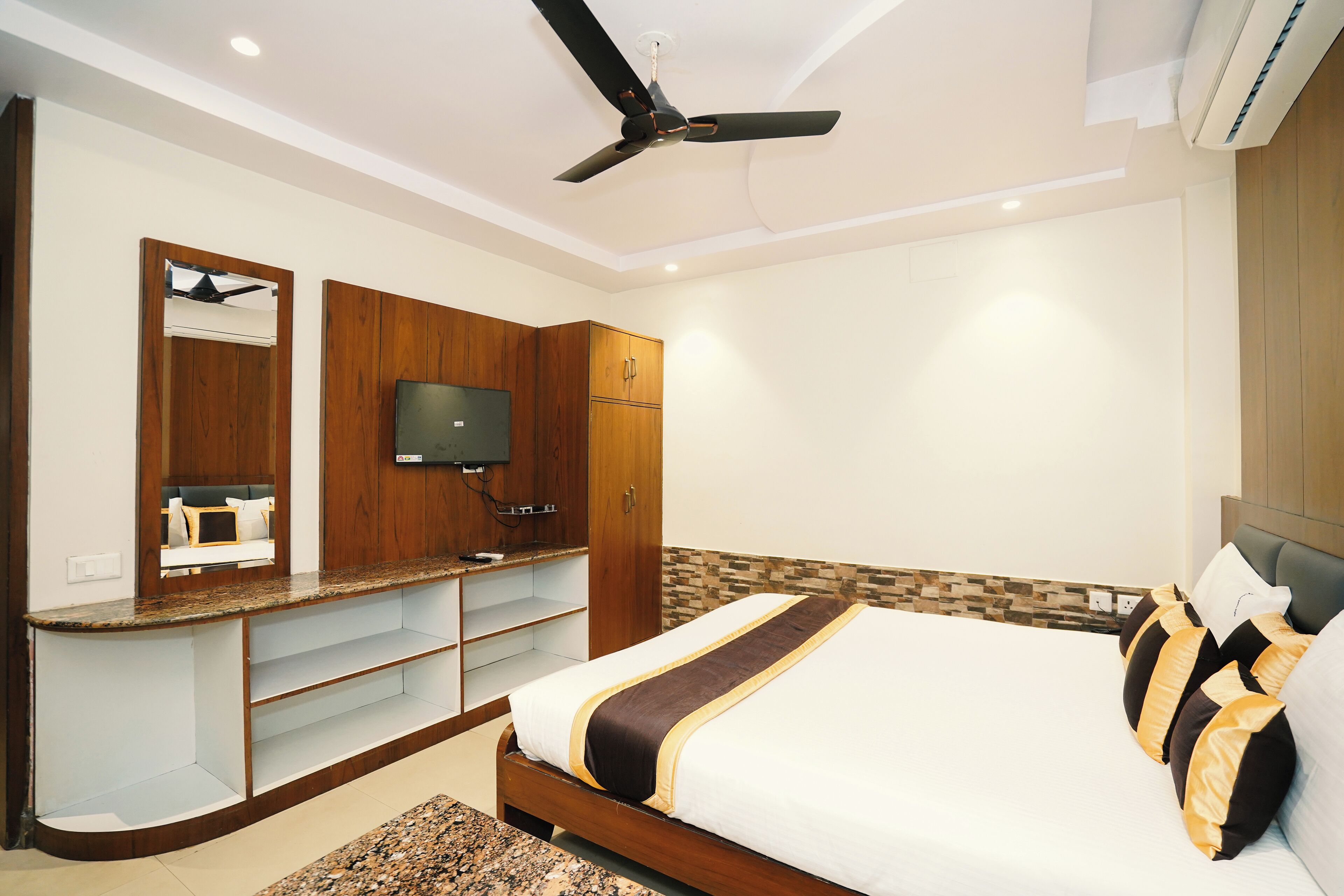 A bedroom with a bed, a TV, wooden cabinets, and a ceiling fan.