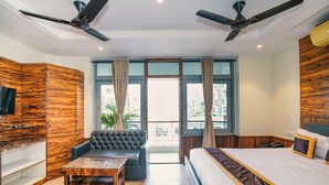 Una habitación de hotel moderna con una cama grande, un sofá, una mesita de centro y un televisor.