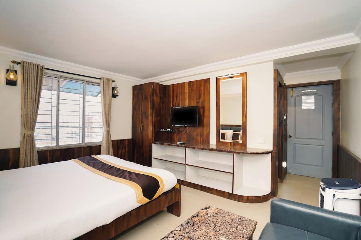 A hotel room with a bed, a TV, a desk, a chair, and a suitcase.