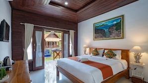 A bedroom with a wooden bed, a painting, and a view of the outdoors. - Arjuna Bungalow (Penida Island)