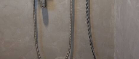 Ducha empotrada en la pared con mando giratorio y cabezal de ducha de mano.