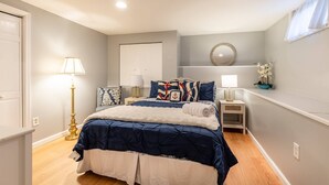 Een slaapkamer met een bed, nachtkastjes, een lamp, een spiegel en een klein plankje met een plant.
