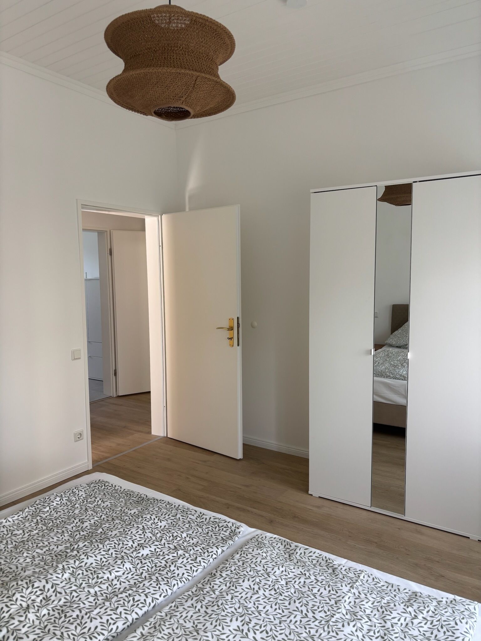 A bedroom with a bed, a wardrobe, and a hanging light fixture.