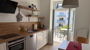 Une cuisine moderne dotée de plans de travail en bois, d’un four encastré, d’un lave-vaisselle et d’une fenêtre donnant sur un balcon.
