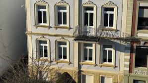 Un immeuble à plusieurs étages, doté d’une façade symétrique, avec des fenêtres régulièrement espacées, agrémentées de moulures décoratives, et un balcon central orné de balustrades en fer forgé.