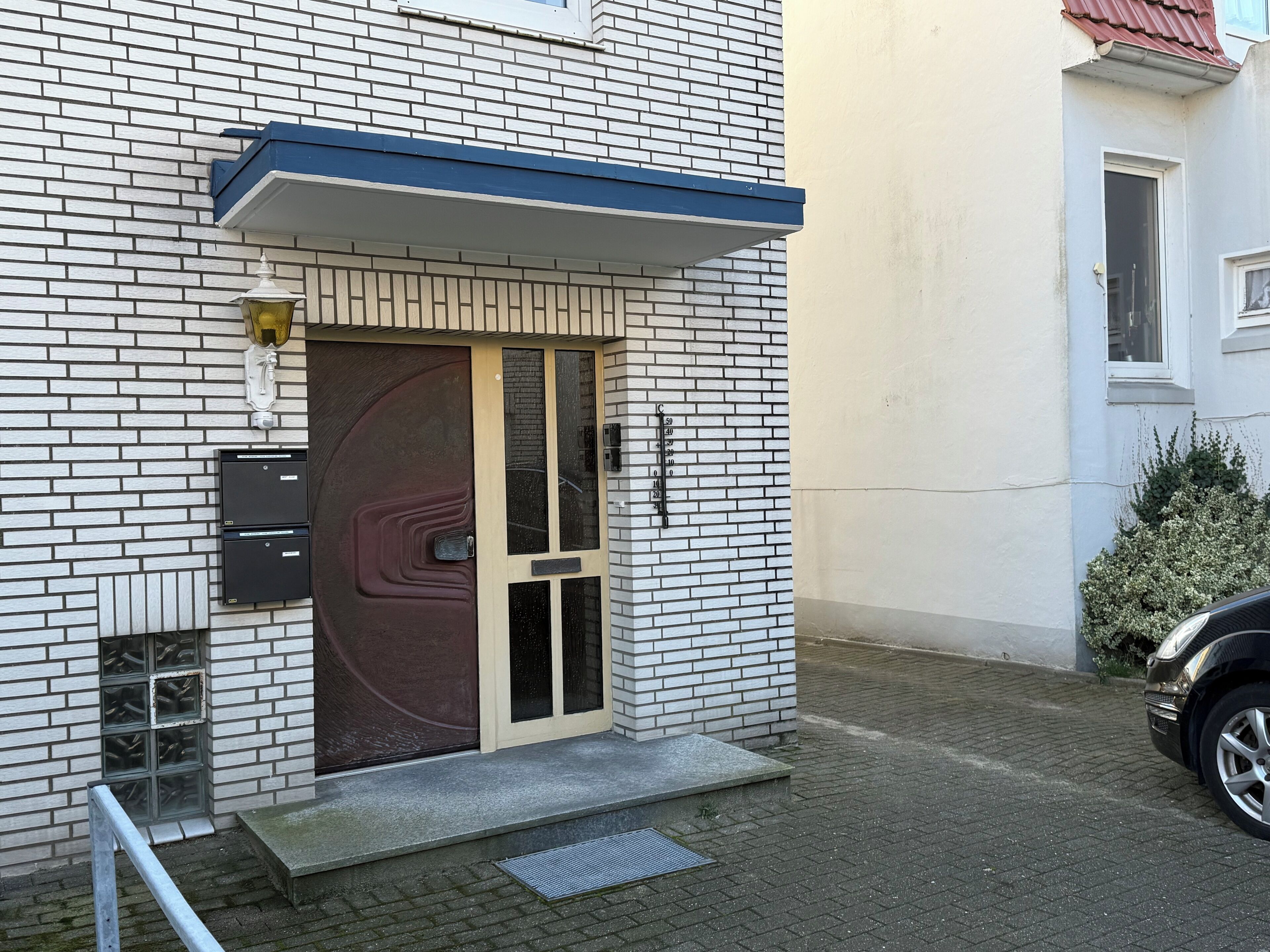 A building with a brick facade, a large door with a glass panel, and a small step leading to the entrance.