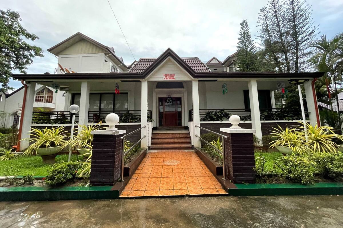 A two-story building with a covered entrance and a tiled walkway leading to the door.
