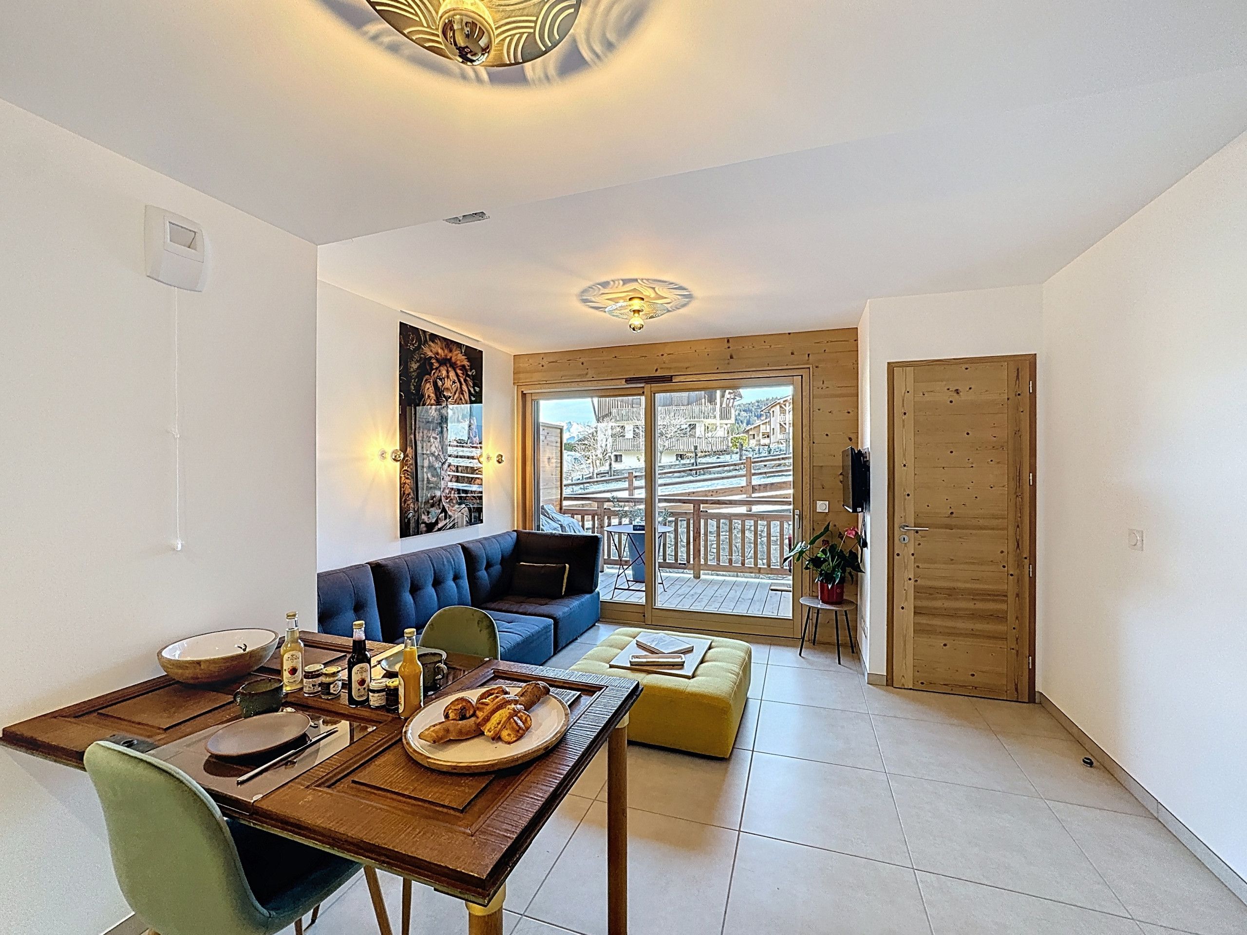 A modern living room with a sofa, dining table, and a view of a wooden deck.