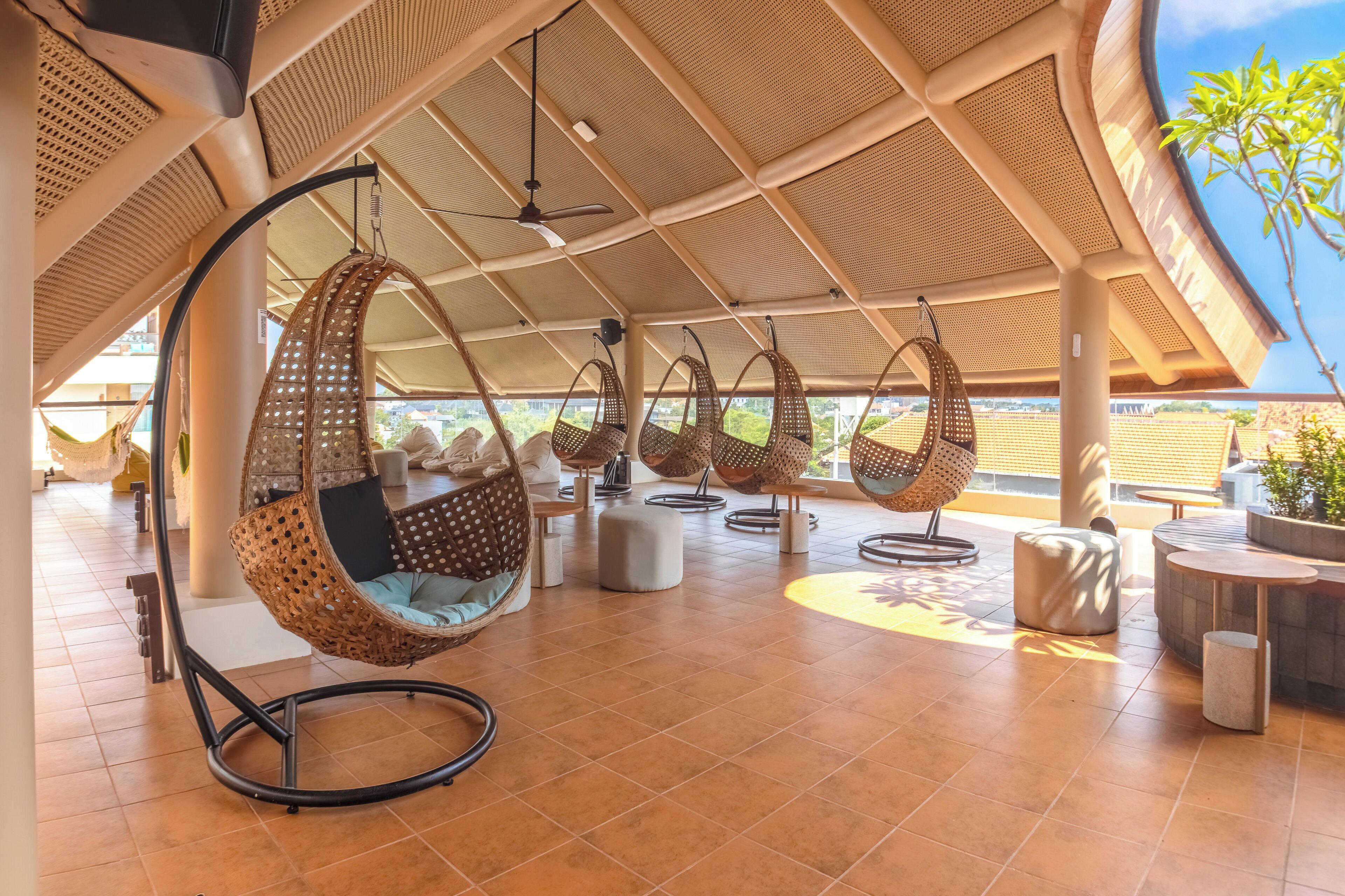 Un amplio espacio al aire libre con sillas colgantes y piso de baldosas.