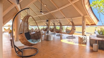 Un amplio espacio al aire libre con sillas colgantes y piso de baldosas.