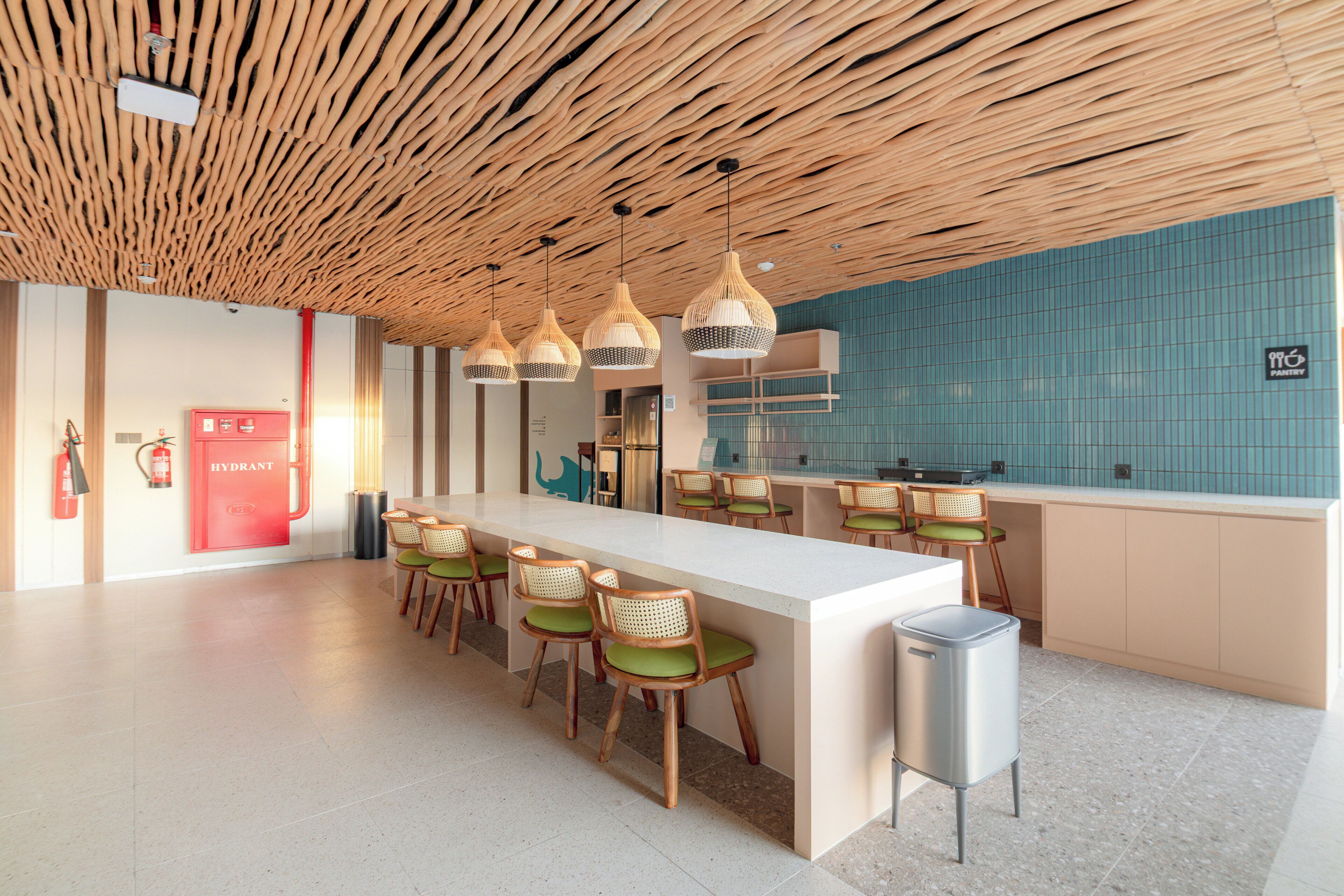 A modern kitchen with a wooden ceiling, a long counter, and green cushioned chairs.