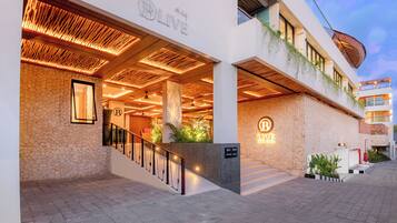 Entrada de hotel con fachada de piedra, techo de madera y un cartel que dice 'LIVE COLIVING'.