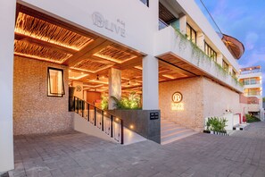 A hotel entrance with a stone facade, a wooden ceiling, and a sign that reads 'LIVE COLIVING'. - BLive Coliving Canggu (Canggu)