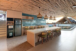 A modern kitchen with a central island, bar stools, and a built-in refrigerator. - BLive Coliving Canggu (Canggu)