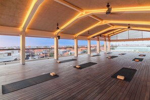 A spacious rooftop deck with wooden flooring, yoga mats, and a city view. - BLive Coliving Canggu (Canggu)
