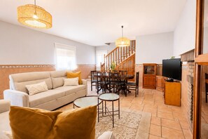 A living room with a sofa, coffee table, TV, dining area, and staircase. - Comeback El Patio de mi Recreo (Motril)