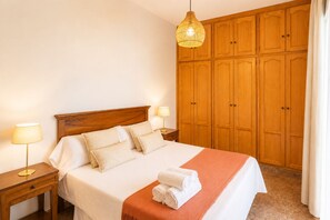 A hotel room with a wooden bed, two bedside lamps, a large wardrobe, and a hanging light fixture. - Comeback El Patio de mi Recreo (Motril)