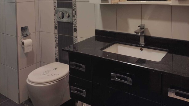 Un baño con inodoro, lavabo, espejo y toallero.