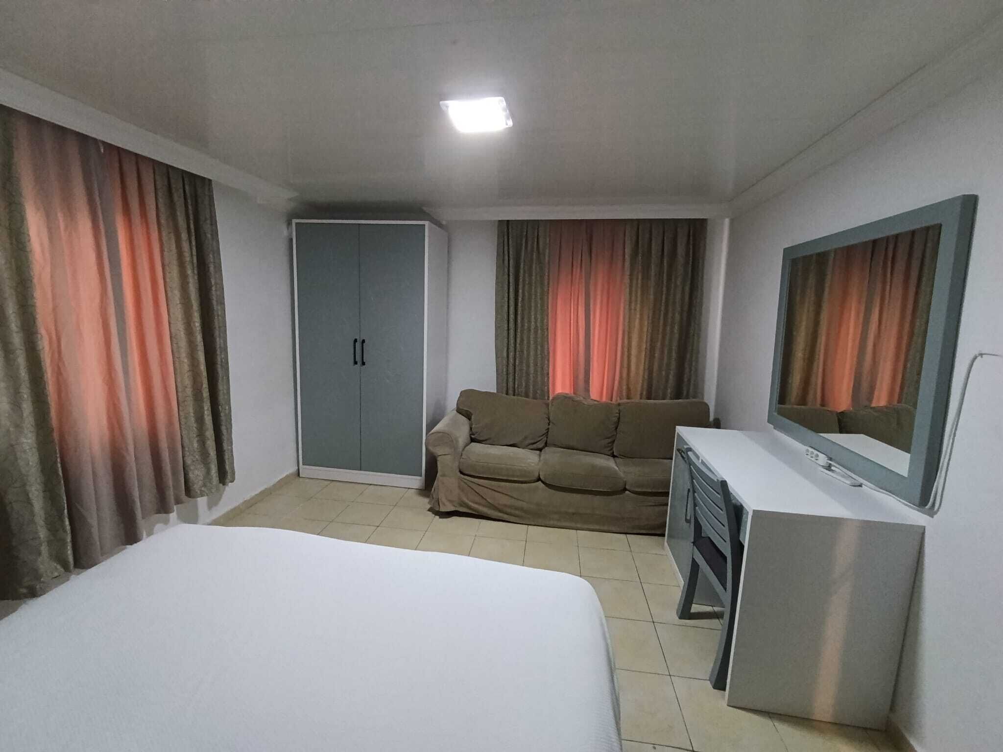 Une chambre d’hôtel comprenant un lit, un canapé, un bureau, un miroir et une armoire.