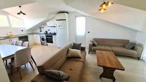 Een knus woongedeelte met een kitchenette, een bank, een eettafel en een houten salontafel.